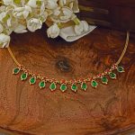 Traditional gold Nagapadam necklace with green teardrop pendants and red stone floral connectors.