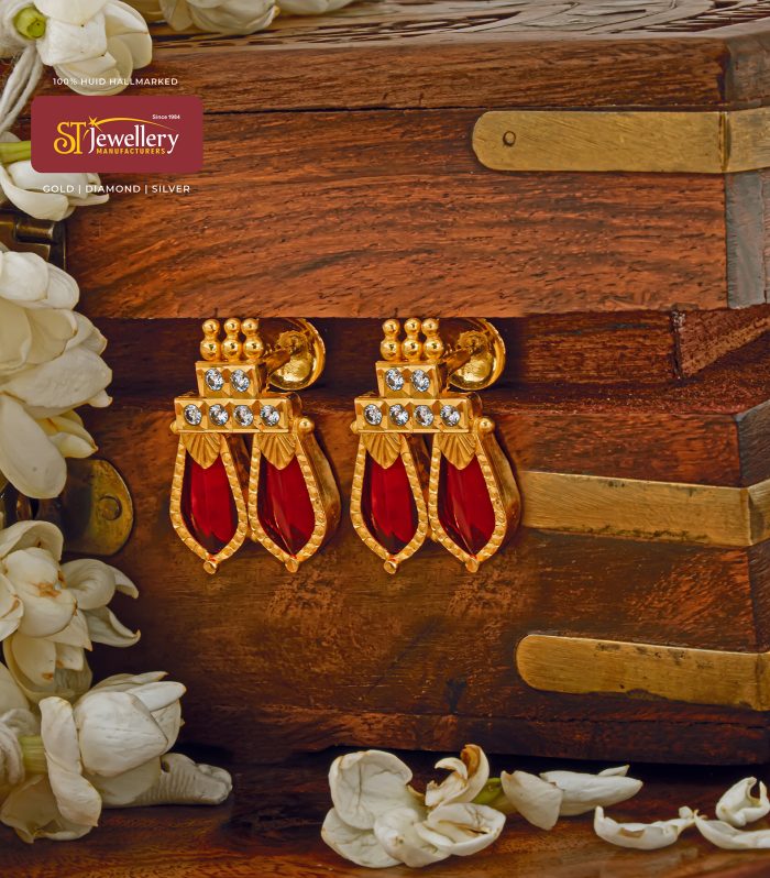 Traditional gold drop earrings with red teardrop stones and clear crystal accents in geometric setting.
