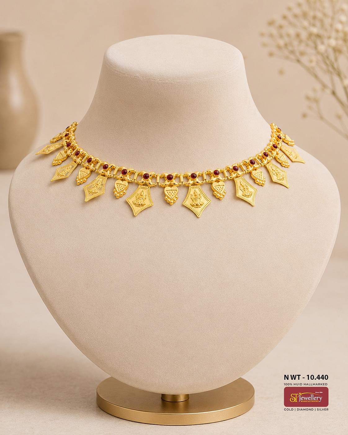 Traditional gold temple necklace featuring Lakshmi motifs, ruby accents, and intricately engraved hanging charms in an antique finish.