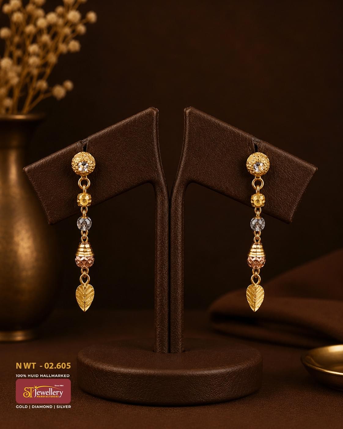 Elegant gold drop earrings with sparkling crystal accents, textured gold beads, dual-tone detailing, and leaf-shaped dangling charm for festive and everyday wear.