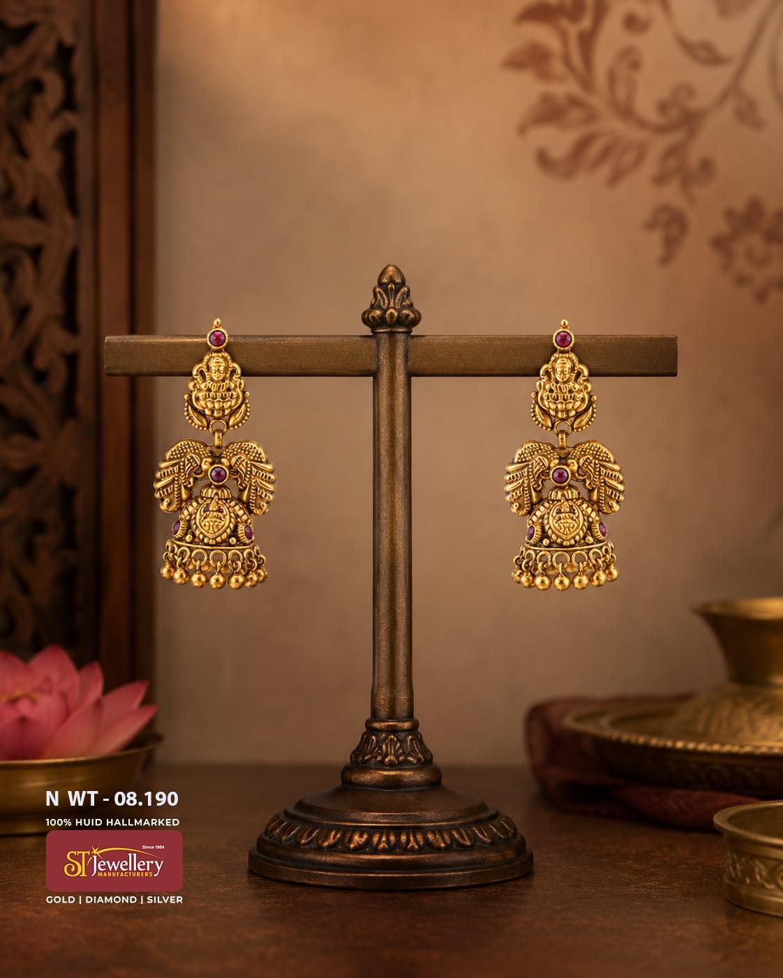 Antique Lakshmi temple gold jhumka earrings featuring intricate peacock motifs, Goddess Lakshmi design, ruby stone accents, handcrafted antique finish, and traditional South Indian bridal jewellery.