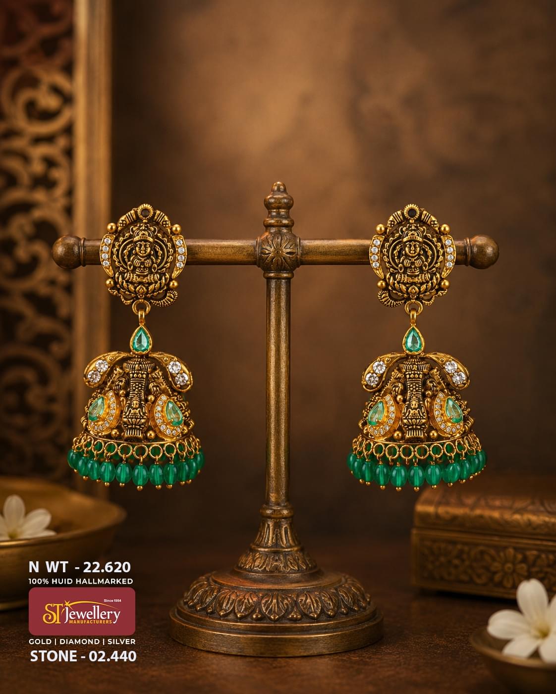 Antique temple gold jhumka earrings featuring Goddess Lakshmi motifs, emerald green stones, CZ diamond accents, and green bead danglers in traditional South Indian bridal jewellery design.