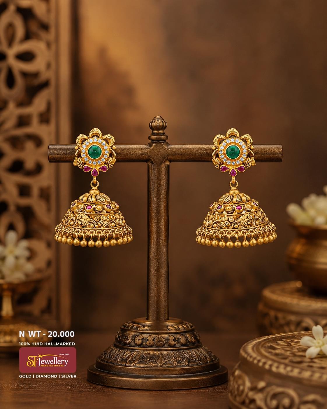 Traditional antique gold jhumka earrings with green center stones, ruby accents, intricate handcrafted dome design, and classic South Indian temple jewellery craftsmanship.