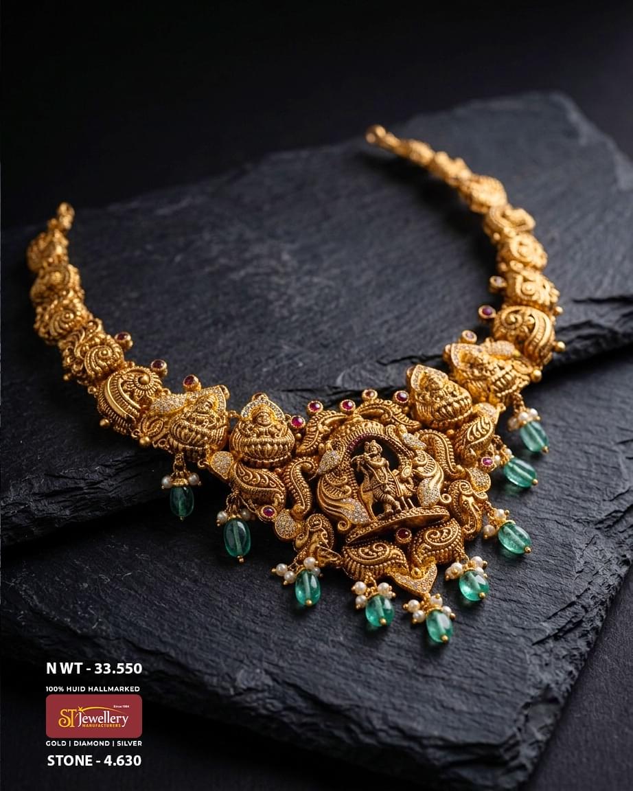 Traditional antique temple gold necklace featuring an intricately carved Lord Krishna centerpiece, Lakshmi motifs, emerald green bead drops, pearl accents, and detailed heritage craftsmanship for bridal and festive wear.