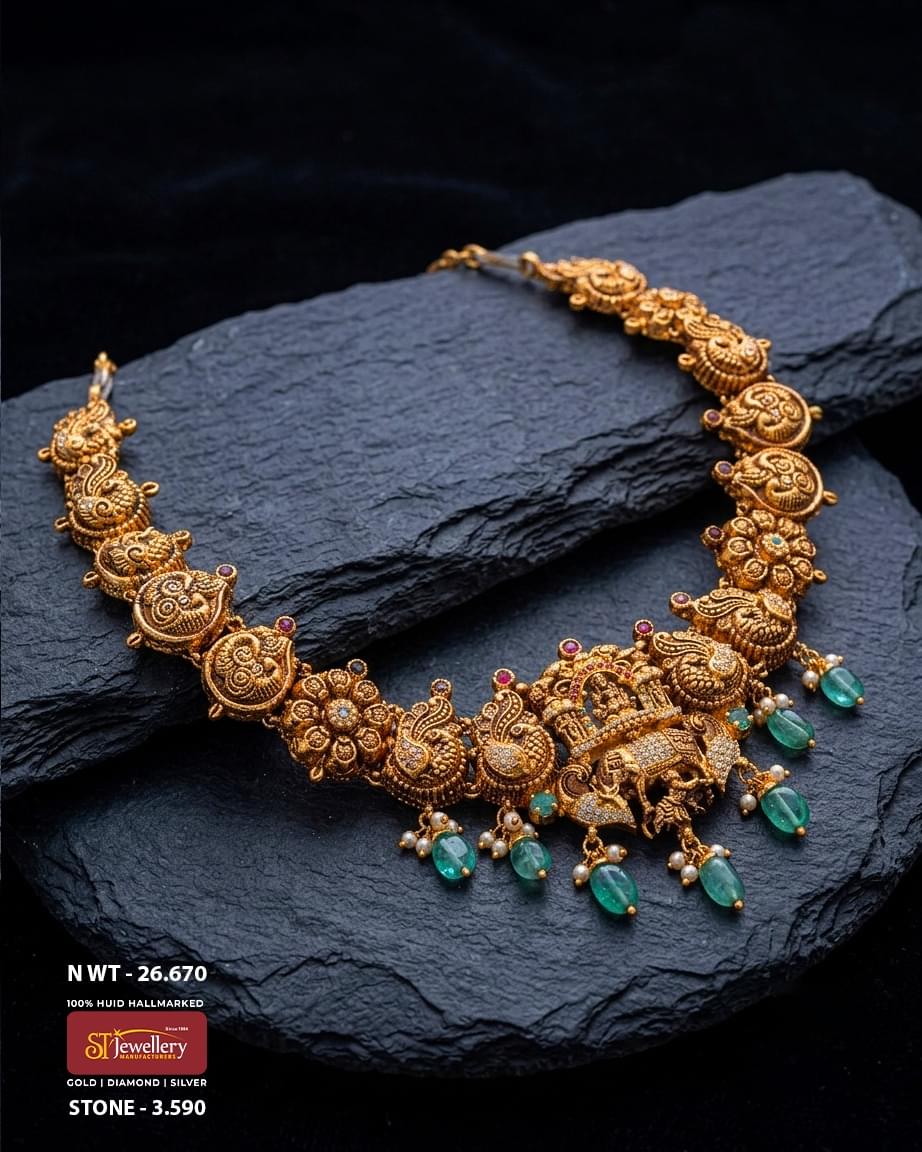 Antique temple gold necklace featuring an intricately crafted royal elephant centerpiece, peacock and floral motifs, emerald green bead drops, pearl accents, and heritage-inspired detailing for bridal and festive wear.
