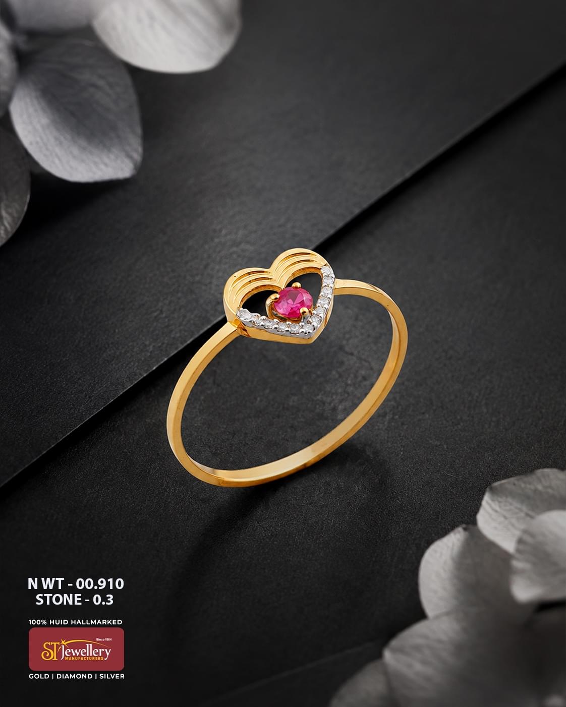 Elegant gold ring featuring a layered heart design with a vivid pink center stone and sparkling white stone accents, displayed on a premium matte black background.