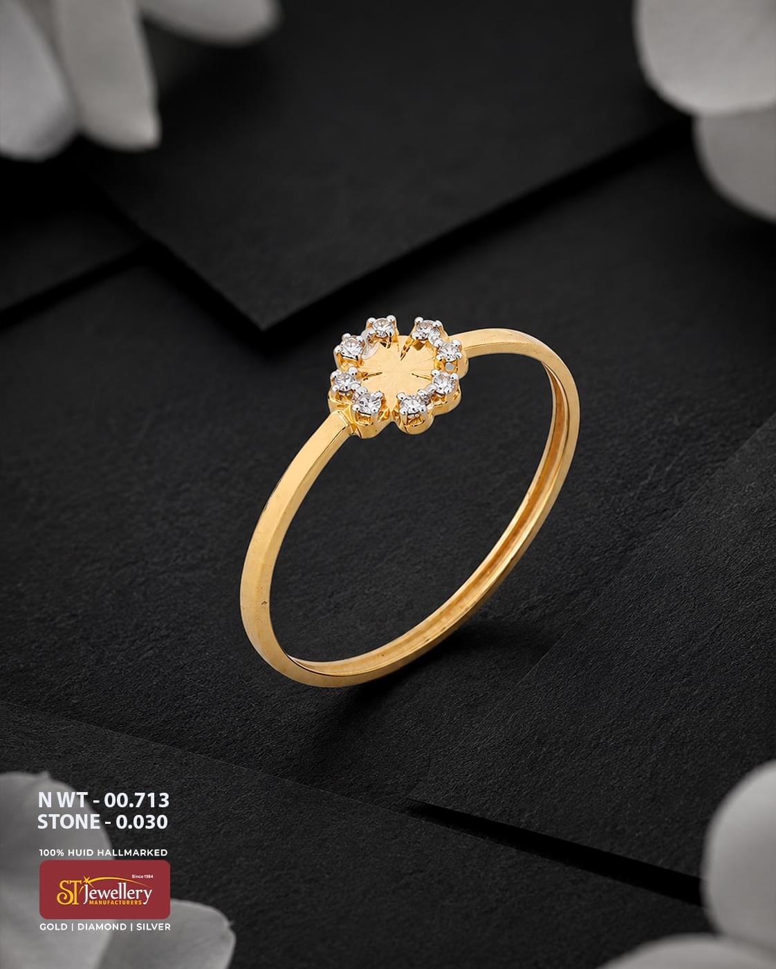 Elegant gold ring featuring a delicate floral design with sparkling white stone accents arranged around a polished gold center, displayed on a premium matte black background.