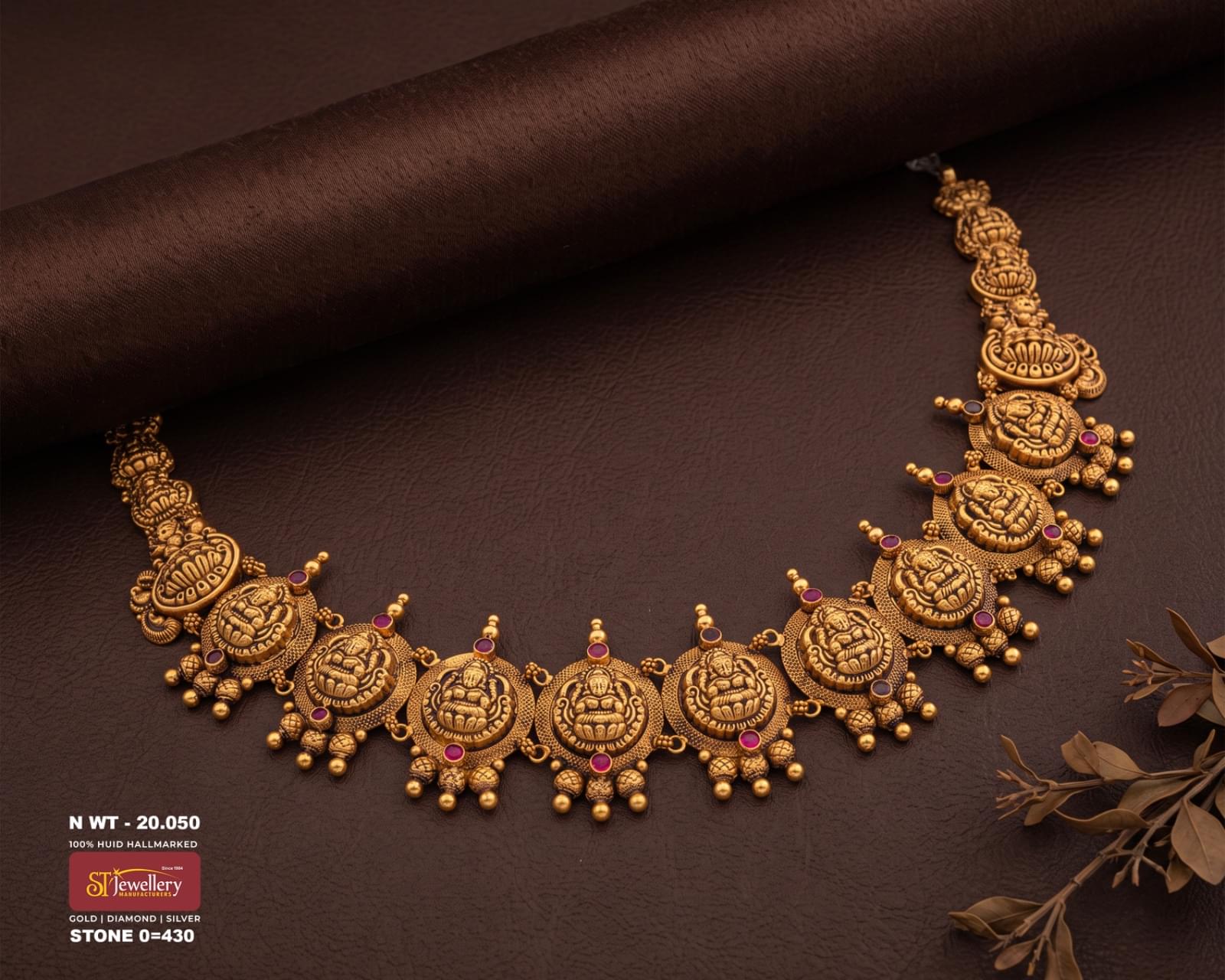 Traditional antique gold temple necklace with detailed goddess motifs, red stone accents, intricate gold beadwork and dangling gold beads.